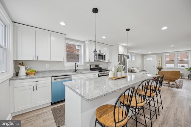 kitchen featuring pendant lighting, appliances with stainless steel finishes, sink, and white cabinets