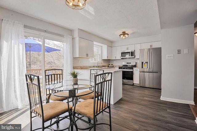 dining space featuring a textured ceiling, baseboards, and dark wood-style flooring