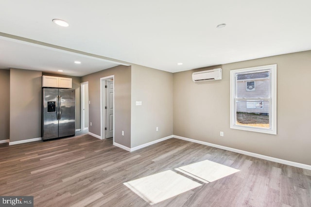 spare room with a wall mounted air conditioner and wood-type flooring