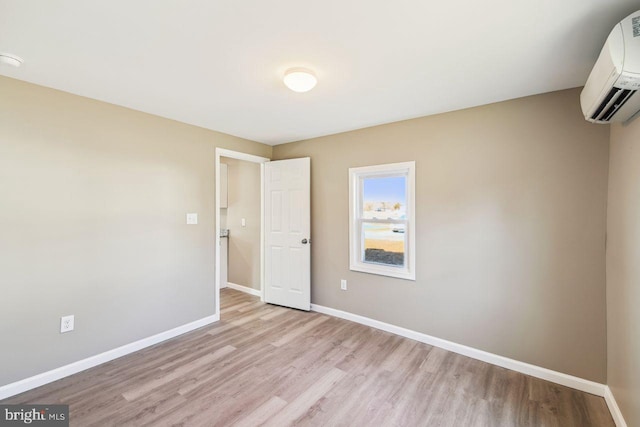 empty room with light hardwood / wood-style flooring and a wall unit AC