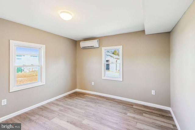 empty room featuring light wood-type flooring and a wall mounted air conditioner