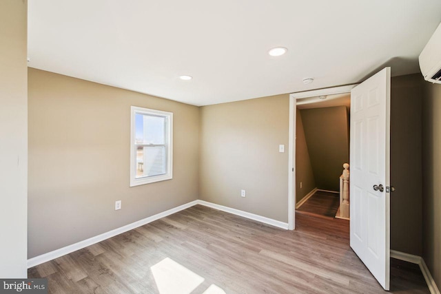 unfurnished bedroom featuring light hardwood / wood-style floors and a wall unit AC