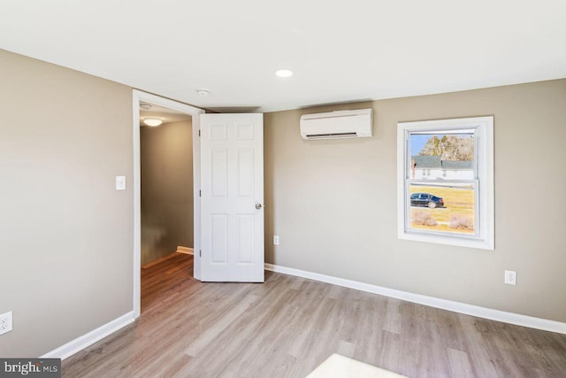 spare room with a wall mounted AC and light hardwood / wood-style flooring