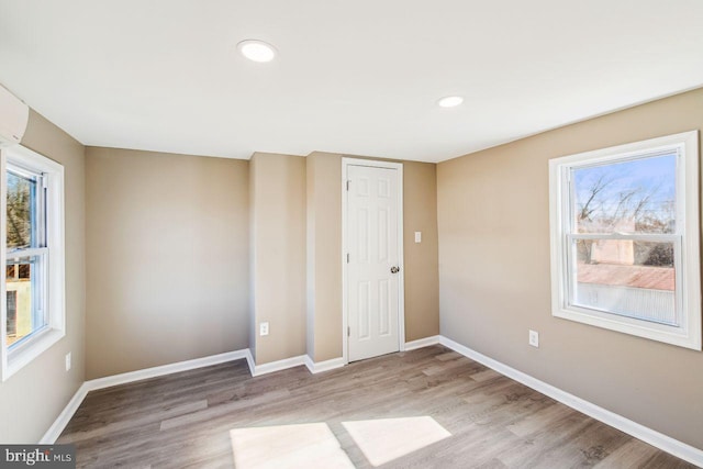 empty room with a wealth of natural light and light hardwood / wood-style flooring