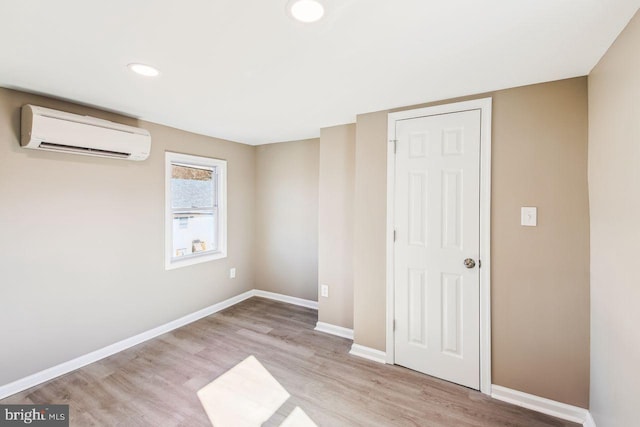 unfurnished bedroom featuring light wood-type flooring and a wall mounted AC