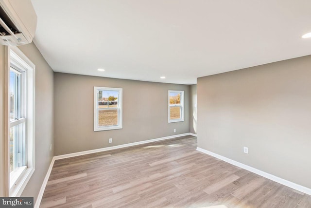 unfurnished room featuring light hardwood / wood-style floors and an AC wall unit