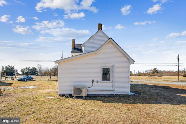 view of side of property with ac unit and a lawn