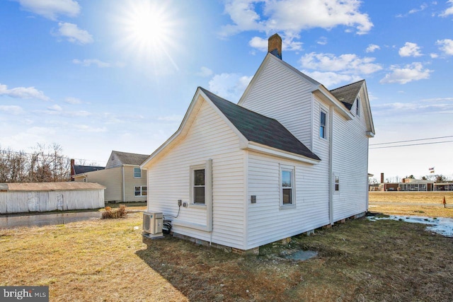 rear view of property with ac unit and a lawn