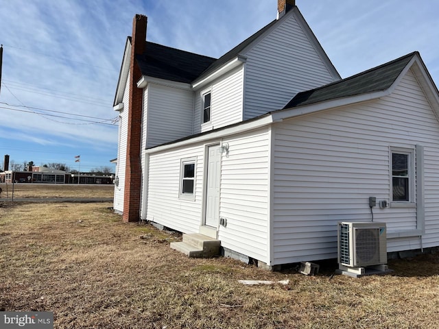 rear view of house with ac unit and a lawn