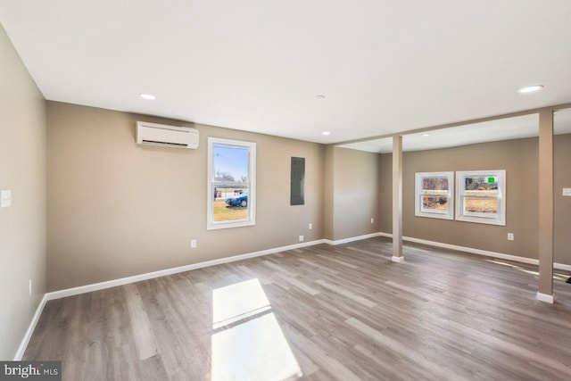 empty room with an AC wall unit, plenty of natural light, and wood-type flooring