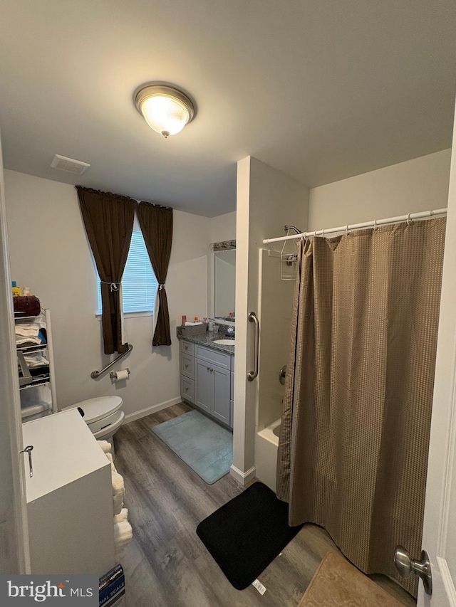 full bathroom with hardwood / wood-style flooring, vanity, shower / bathtub combination with curtain, and toilet