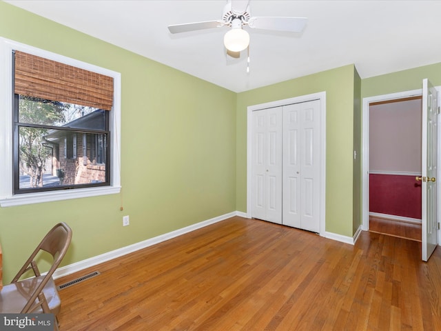 unfurnished bedroom with hardwood / wood-style floors, a closet, and ceiling fan