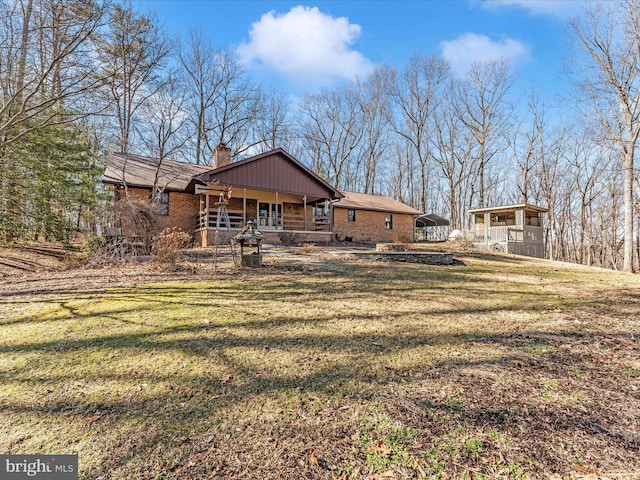 rear view of property featuring a lawn and covered porch