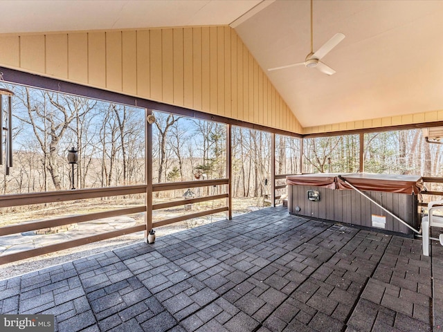 unfurnished sunroom featuring ceiling fan, vaulted ceiling, and a hot tub