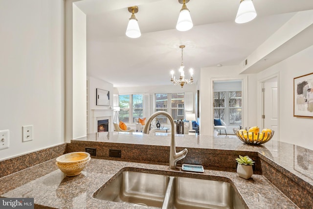 kitchen featuring sink, dark stone counters, a notable chandelier, and decorative light fixtures