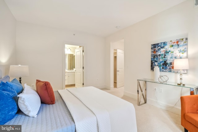 bedroom featuring ensuite bathroom and light colored carpet