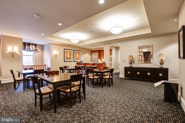 carpeted dining room featuring a tray ceiling and crown molding