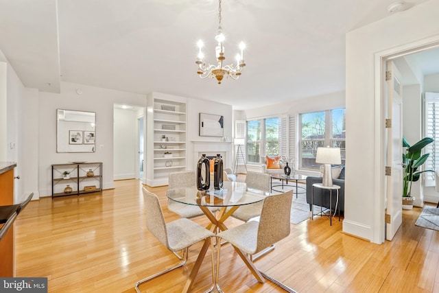 dining space with light hardwood / wood-style flooring, a chandelier, and built in features