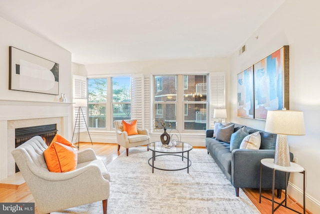 living room featuring light wood-type flooring and a high end fireplace