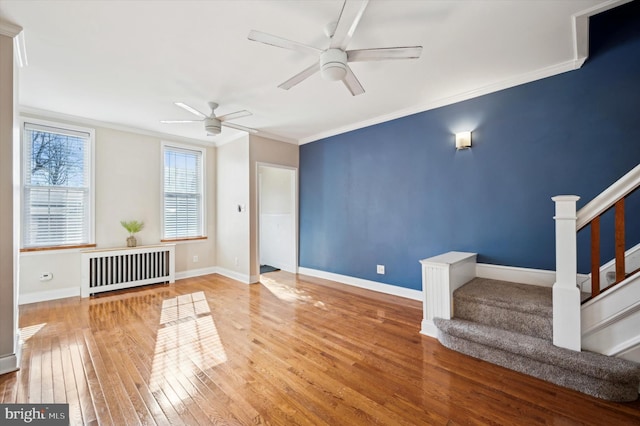 unfurnished living room with hardwood / wood-style flooring, ceiling fan, crown molding, and radiator