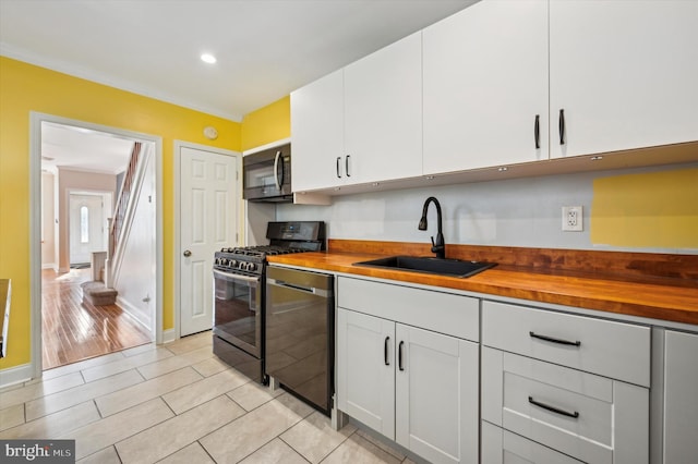 kitchen with gas range oven, dishwasher, sink, and butcher block countertops