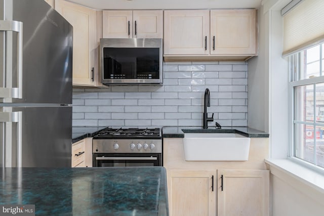 kitchen with tasteful backsplash, appliances with stainless steel finishes, and sink