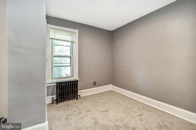 empty room featuring radiator and light carpet