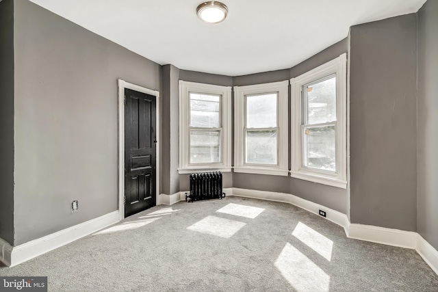 unfurnished room featuring carpet and radiator heating unit