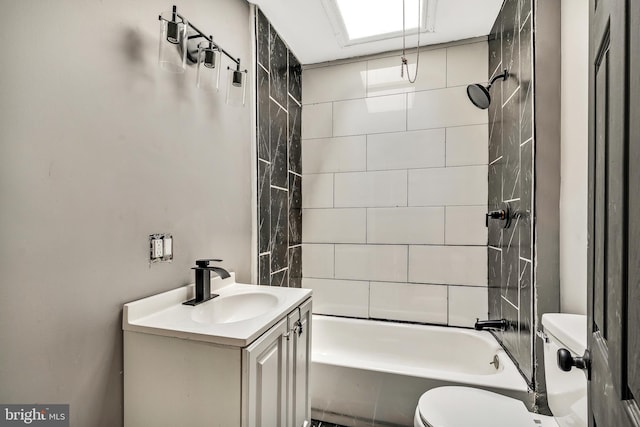 full bathroom featuring tiled shower / bath, vanity, and toilet