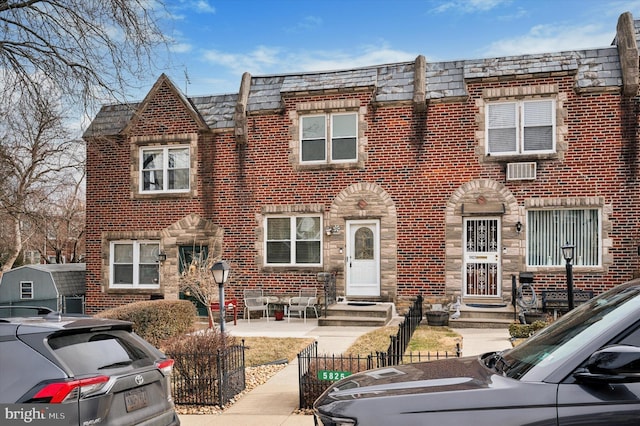 multi unit property featuring a fenced front yard and brick siding