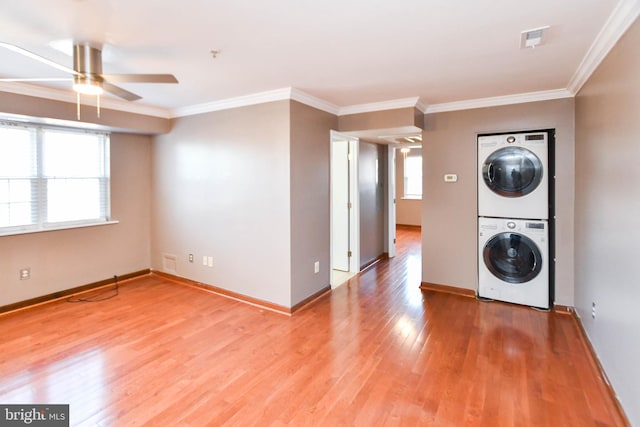 washroom featuring ceiling fan, ornamental molding, stacked washer / drying machine, and light wood-type flooring