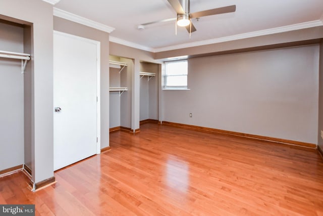 unfurnished bedroom featuring multiple closets, ceiling fan, ornamental molding, and hardwood / wood-style floors