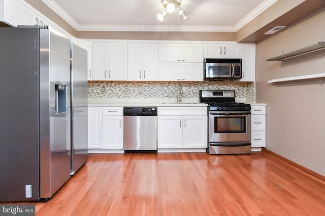 kitchen featuring ornamental molding, appliances with stainless steel finishes, sink, and white cabinets