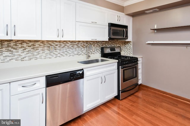 kitchen with sink, white cabinetry, tasteful backsplash, light hardwood / wood-style flooring, and appliances with stainless steel finishes