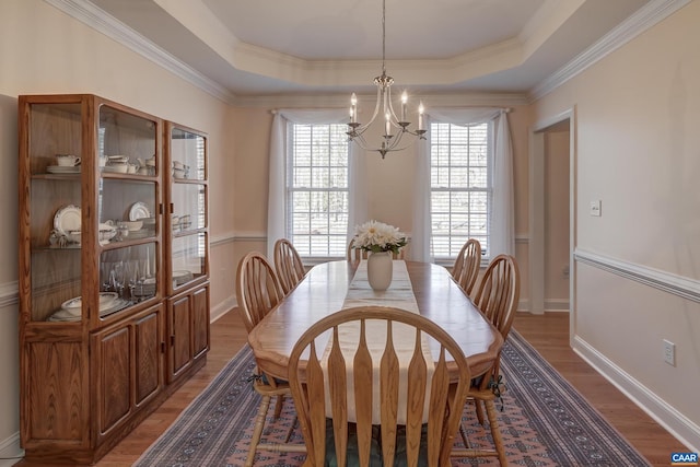 dining area featuring crown molding, hardwood / wood-style flooring, a raised ceiling, and a chandelier