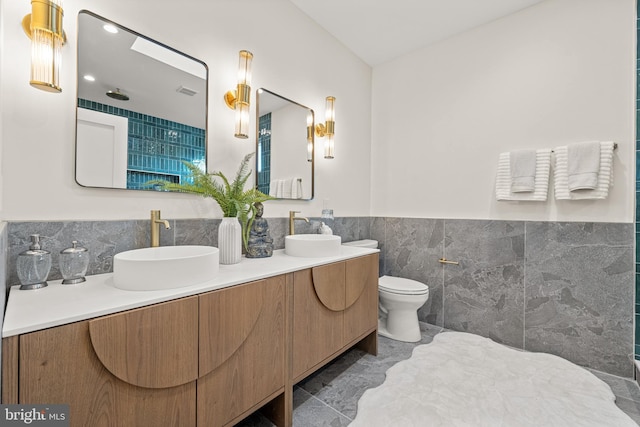 bathroom with vanity, toilet, and tile walls