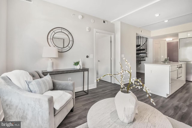 living area with visible vents, baseboards, and dark wood finished floors