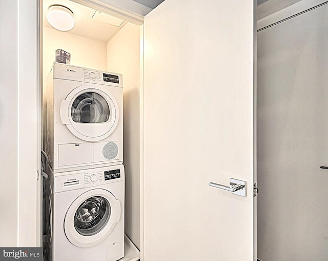 clothes washing area with stacked washer / dryer and laundry area