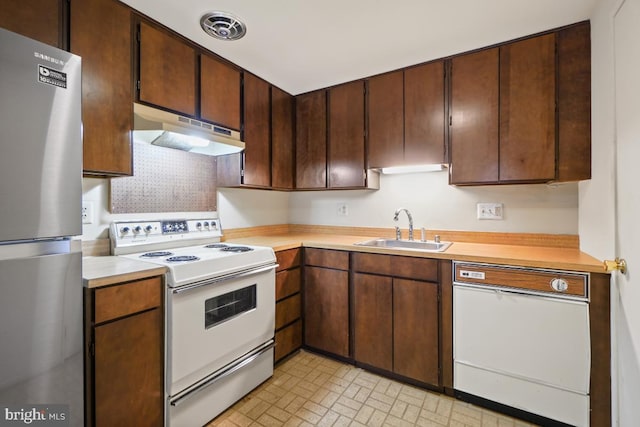 kitchen with white appliances, light countertops, under cabinet range hood, and a sink