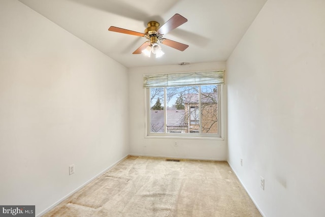 unfurnished room with visible vents, light colored carpet, baseboards, and ceiling fan