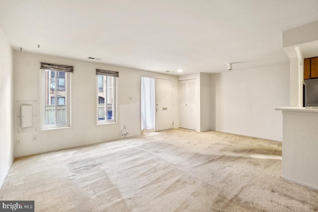 unfurnished living room with visible vents and light colored carpet