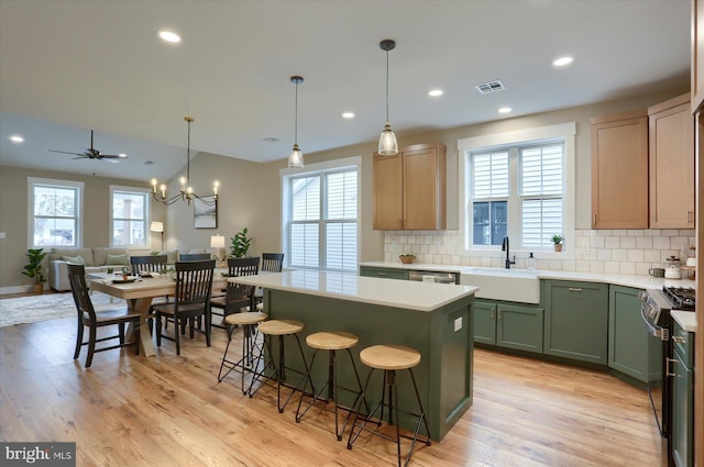 kitchen with sink, backsplash, stainless steel appliances, a center island, and light brown cabinets