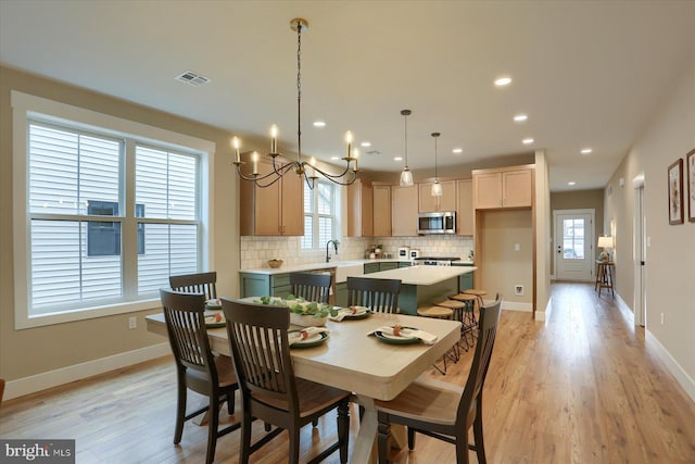 dining space with an inviting chandelier, sink, and light wood-type flooring