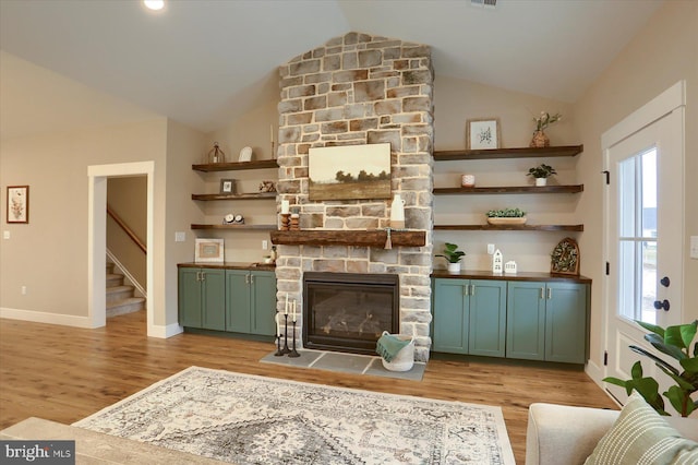 living room featuring high vaulted ceiling, a fireplace, and light hardwood / wood-style floors