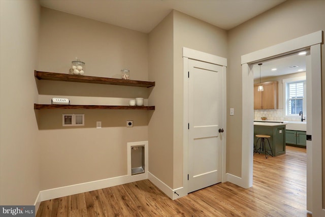 laundry room with hookup for an electric dryer, hookup for a washing machine, sink, and light hardwood / wood-style flooring