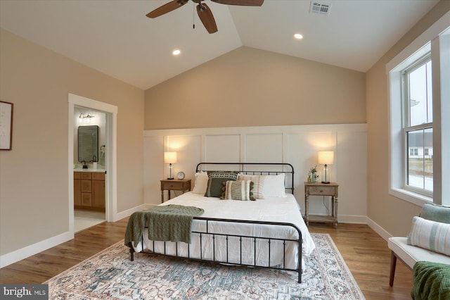 bedroom featuring wood-type flooring, vaulted ceiling, connected bathroom, and ceiling fan