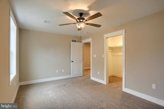 unfurnished bedroom featuring ceiling fan, light colored carpet, a spacious closet, and a closet