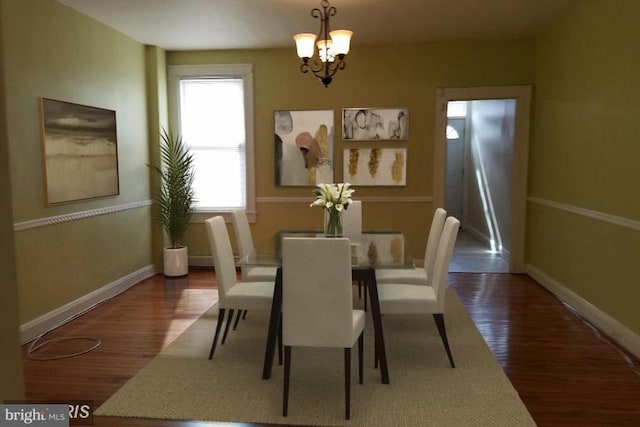 dining area featuring dark wood-type flooring and a chandelier