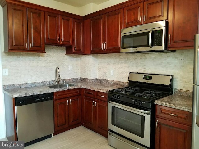 kitchen with tasteful backsplash, sink, stainless steel appliances, and light stone countertops