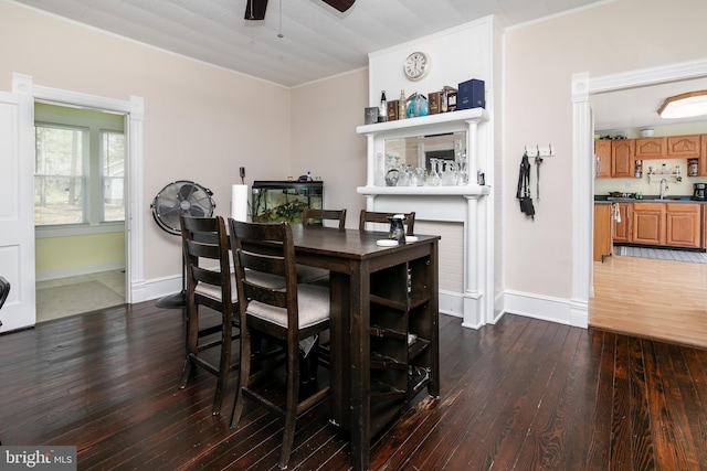 dining space with dark hardwood / wood-style flooring, sink, crown molding, and ceiling fan